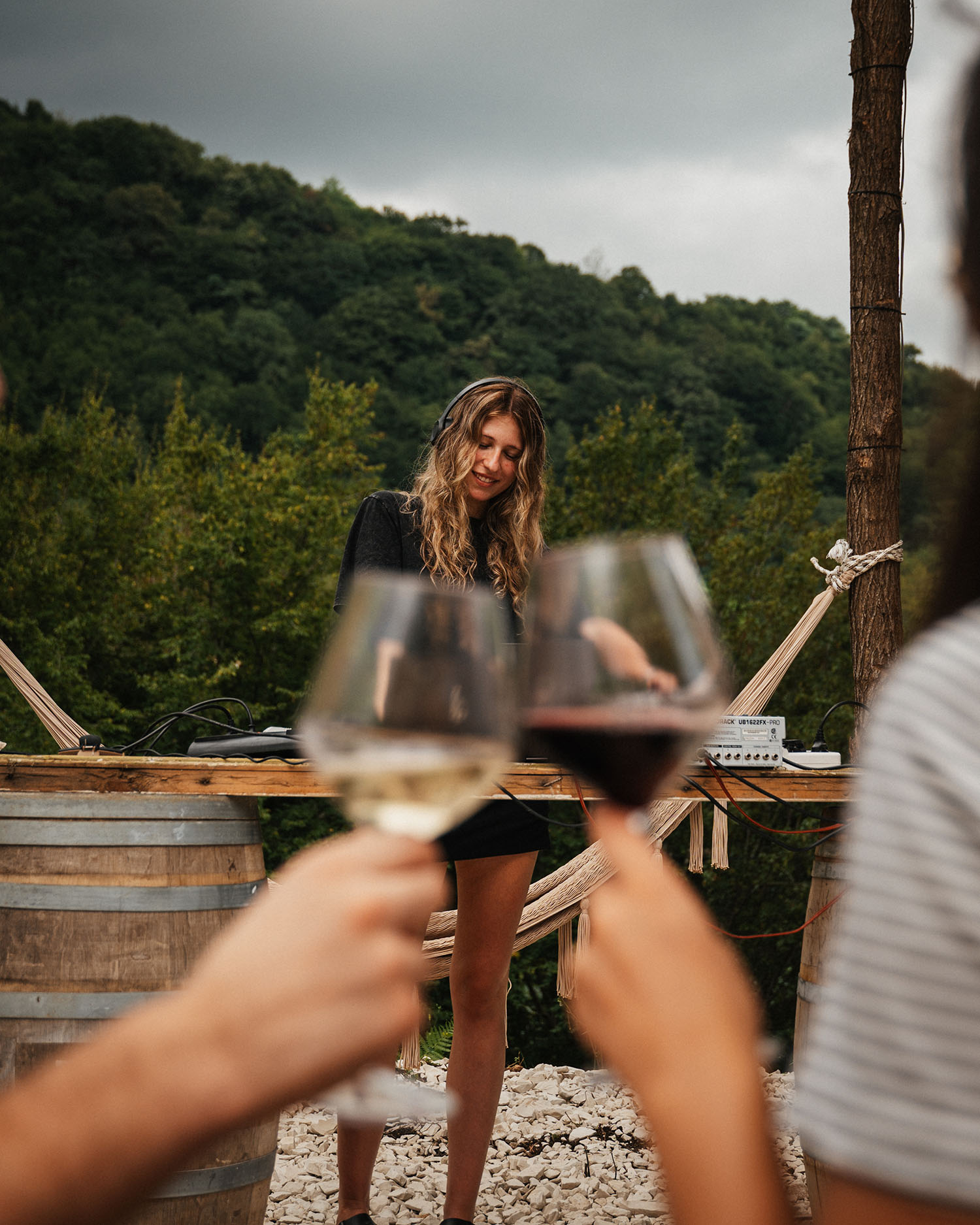 DJ set with wine glasses raised against the forest